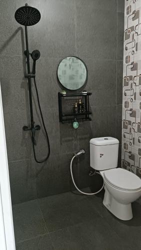 a bathroom with a shower with a toilet and a clock at Villa Kanaya in Sukapura