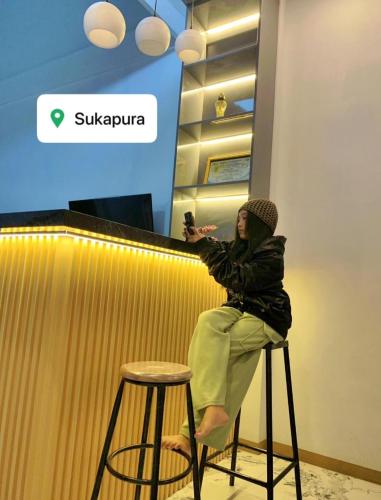 a woman sitting on a stool at a bar at Villa Kanaya in Sukapura