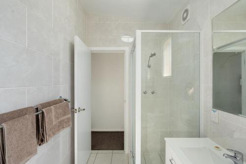a white bathroom with a shower and a sink at Royal Motel Tenterfield in Tenterfield