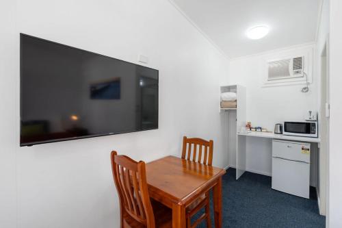 a kitchen with a table and two chairs and a television on a wall at Royal Motel Tenterfield in Tenterfield