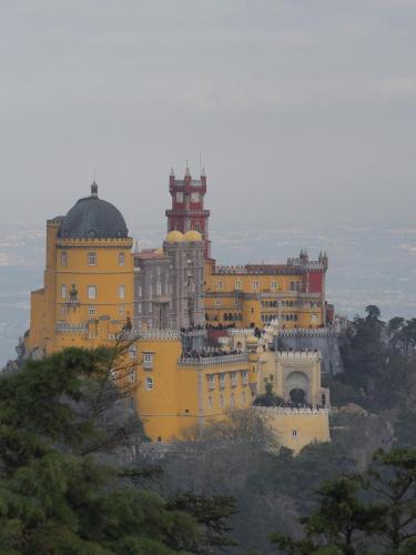 a large yellow building on top of a hill at Casa de Colares - Sintra Beach Pool Surf Getaway Work and Play in Colares