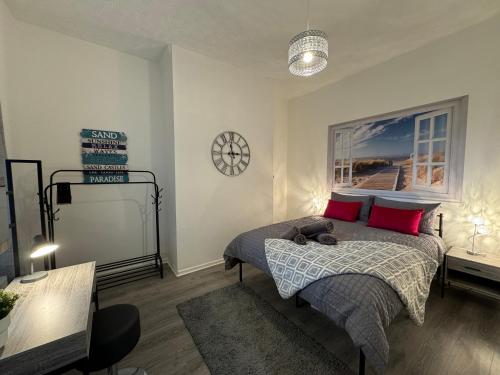 a bedroom with a bed with red pillows and a clock at Station Retreat Cullercoats Free Onsite Parking in Cullercoats