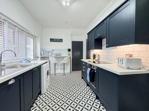 a kitchen with black cabinets and a sink and a dishwasher at Station Retreat Cullercoats Free Onsite Parking in Cullercoats