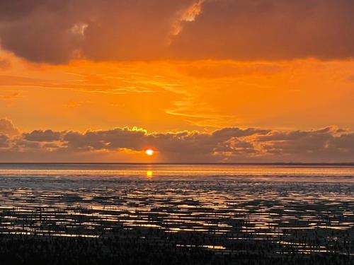 an image of a sunset over the ocean at Tussen Wad en Dijk - Vakantieappartement in Sint Jacobiparochie