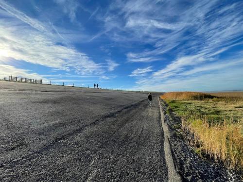 a person riding a bike down a dirt road at Tussen Wad en Dijk - Vakantieappartement in Sint Jacobiparochie