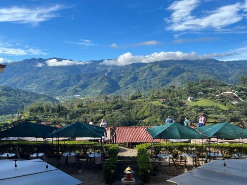 a view of the mountains from a restaurant with tables and umbrellas at Hotel Orocay Lodge in Cartago