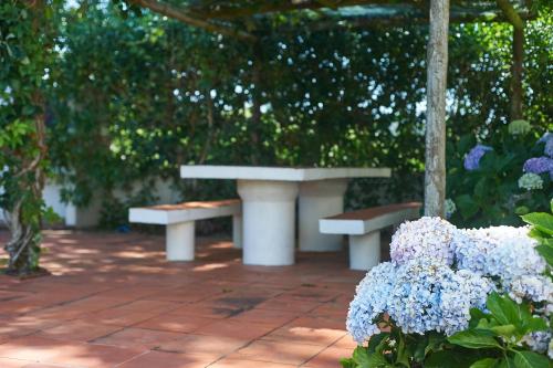 two benches sitting on a brick patio with flowers at Casa de Colares - Sintra Beach Pool Surf Getaway Work and Play in Colares