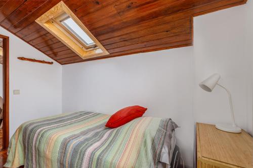 a bedroom with a bed with a red pillow on it at Casa de Colares - Sintra Beach Pool Surf Getaway Work and Play in Colares