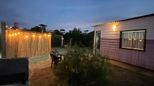 a backyard with a house and a fence with lights at Casa Violeta Punta del Diablo in Punta Del Diablo