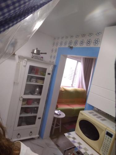 a small room with a microwave and a room with a bed at Apto com charme conforto vista e completo in Florianópolis