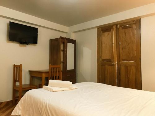 a bedroom with a bed and a desk and a television at Nafis Casona Apu Linli Pisac in Pisac