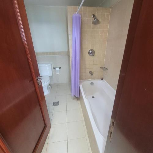 a bathroom with a tub and a toilet with a purple shower curtain at Royal Beach in King Abdullah Economic City