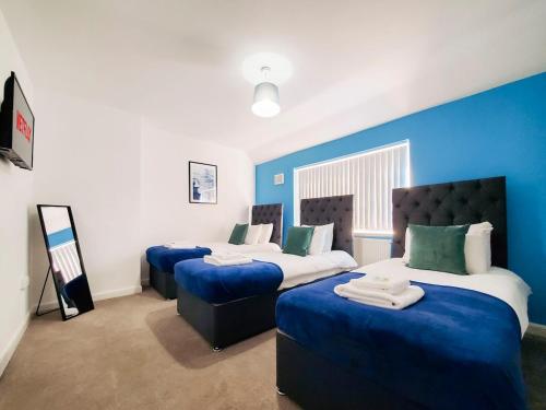 two beds in a room with blue walls at Spacious 3 Bedroom Home - Near Nec, Birmingham Airport & Solihull in Birmingham