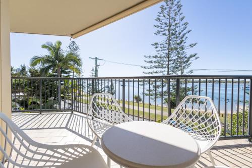 a balcony with two chairs and a table and a tree at Bayview Beach Holiday Apartments in Gold Coast