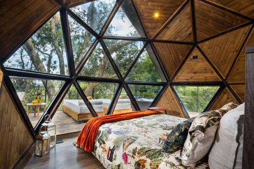 a bedroom in a tree house with a large window at GreenOriental Resort in La Vega