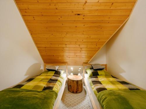 two beds in a room with a wooden ceiling at Villa in Varva ov with Garden and Barbecue in Varvažov