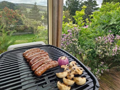 a grill with some meat and an apple and mushrooms at Romantic Retreat Pod by Historic Church on Wine Route in Bangor