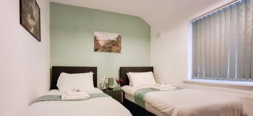 zwei Betten in einem Zimmer mit Fenster in der Unterkunft Charming 3-Bedroom Home Near NEC, Birmingham Airport & Bullring in Birmingham