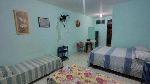 a bedroom with two beds and a table in it at Refúgio da Mangueira in Barra dos Coqueiros