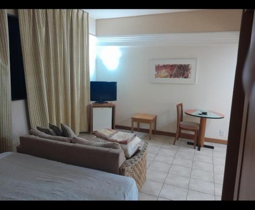 Habitación de hotel con sofá, mesa y TV en Tropical Business, en Manaus