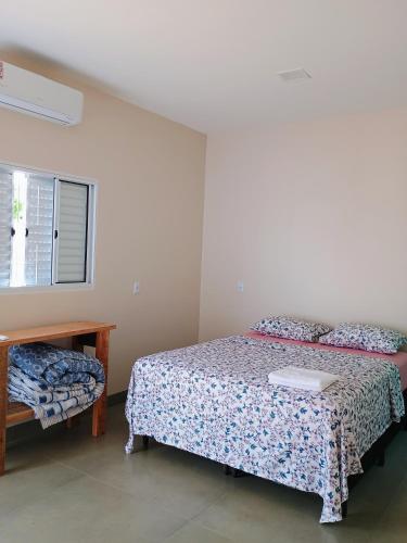 a bedroom with a bed and a table and a window at Pousada Zero Três - 03 in Chapada dos Guimarães