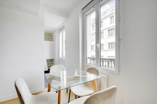 une salle à manger avec une table en verre et des chaises blanches dans l'établissement Résidence Antoine - 2P ou 4P -Bastille, à Paris