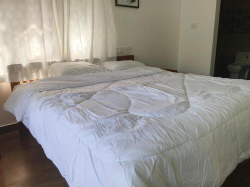 a large white bed sitting in a bedroom at MANAPURATH Homestay in Mamalakandam