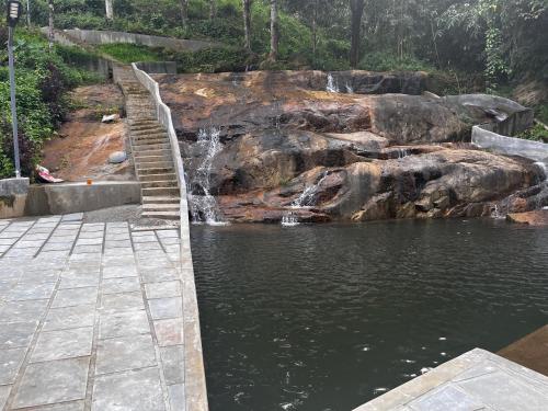 a pond with a waterfall and stairs in a park at MANAPURATH Homestay in Mamalakandam