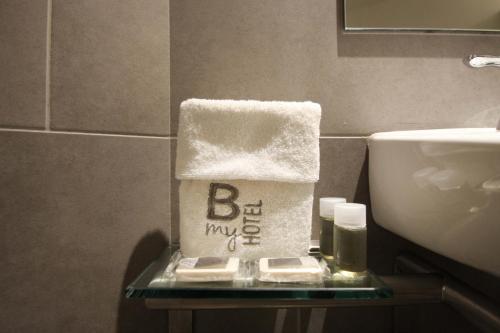 - une boîte de serviettes sur une table en verre à côté d'un lavabo dans l'établissement B my Hotel, à Tijuana