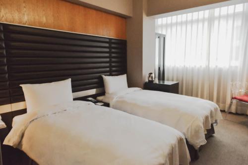 ein Hotelzimmer mit zwei Betten und einem Fenster in der Unterkunft 新麗旅店 Newful Hotel in Taipeh