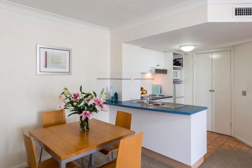 a kitchen with a table with a vase of flowers at Oaks Gold Coast Calypso Plaza Suites in Gold Coast