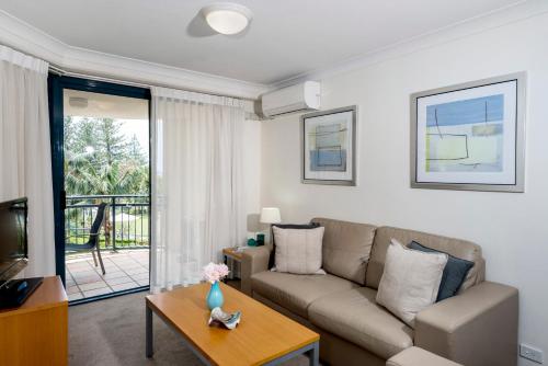 a living room with a couch and a table at Oaks Gold Coast Calypso Plaza Suites in Gold Coast