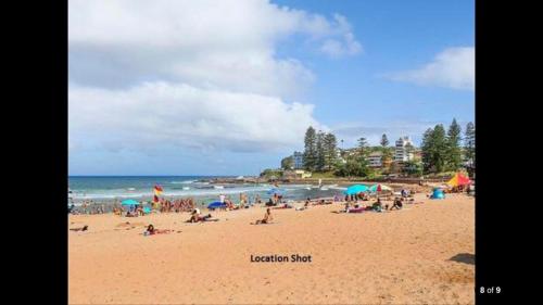 a group of people on a beach with the ocean at 2 bedroom Beach cafes shops bus all a walk away in Deewhy