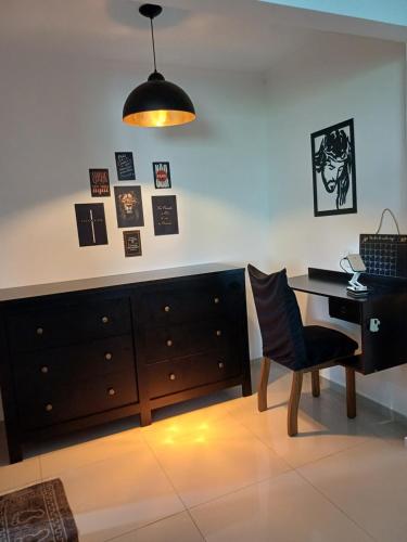 a room with a desk and a chair next to a dresser at Pousada Tia Rosi com suites independente 100 mts da praia c ar, energia solar e atendimento vip in Rio das Ostras