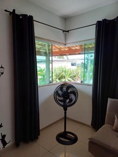 a room with a fan in front of a window at Pousada Tia Rosi com suites independente 100 mts da praia c ar, energia solar e atendimento vip in Rio das Ostras