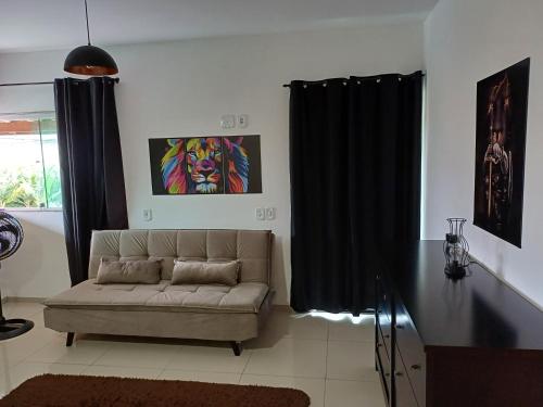 a living room with a couch and a painting at Pousada Tia Rosi com suites independente 100 mts da praia c ar, energia solar e atendimento vip in Rio das Ostras