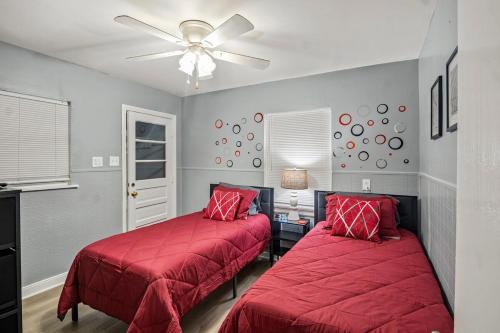 una camera da letto con due letti con coperte rosse e un ventilatore a soffitto di Central RVA Home 4 Bed, 3 Bath Getaway! a Richmond