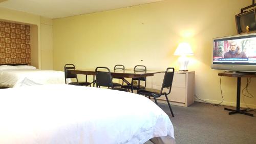 a hotel room with a table and a flat screen tv at Hotel Motel Penn-Mass in Trois-Rivières