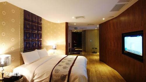a bedroom with a bed and a flat screen tv at Chimei Fashion Hotel in Zhongli
