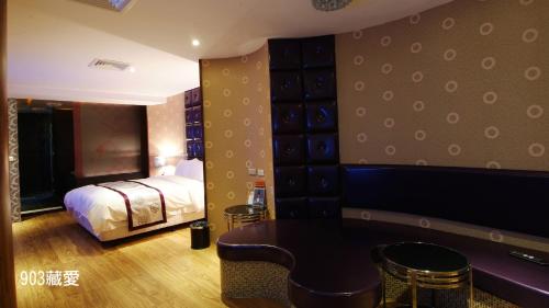 a bedroom with a bed and a table and chairs at Chimei Fashion Hotel in Zhongli
