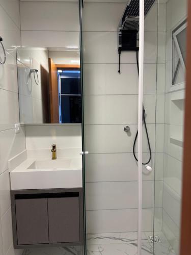 a bathroom with a sink and a glass shower at Apartamento novo em Matinhos 2 piscinas in Matinhos