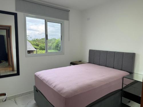 a bedroom with a pink bed and a window at Apartamento novo em Matinhos 2 piscinas in Matinhos