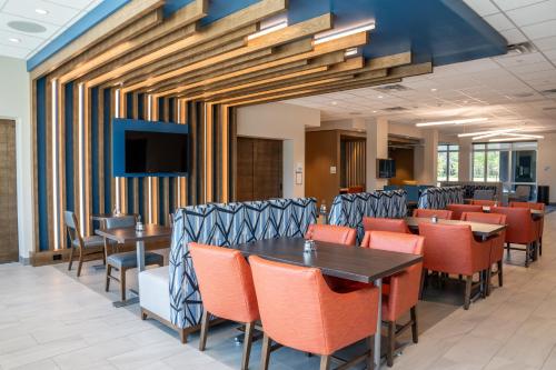 a dining room with tables and chairs and a flat screen tv at Holiday Inn Express & Suites Fort Walton Beach - Eglin Area by IHG in Fort Walton Beach