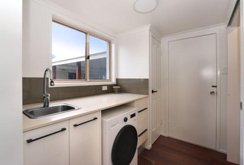 a white kitchen with a sink and a window at 6 Dooley Street Bargara in Bargara