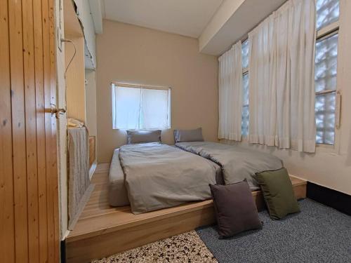 a bedroom with a bed in a room with a window at 可以住Canlive中西區海安路包棟民宿-一日只接待一組 in Tainan