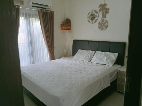 Un dormitorio con una cama con sábanas blancas y una ventana. en Wihmo Villa Bali, en Nusa Dua