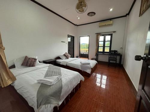 two beds in a room with two windows at Maophasok river side hotel in Luang Prabang