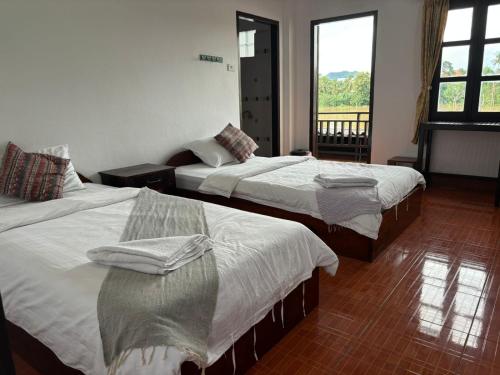 a hotel room with two beds and a window at Maophasok river side hotel in Luang Prabang