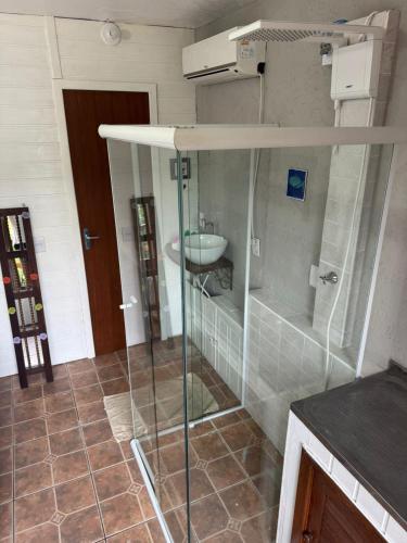 a bathroom with a glass shower and a sink at Pousada Minha Rosa Paixão - PRAIA DO ROSA, SC in Imbituba
