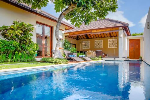 a swimming pool in front of a house at Samana Villas in Legian